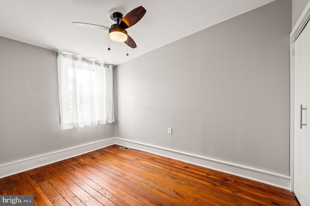 empty room with ceiling fan, visible vents, hardwood / wood-style flooring, and baseboards