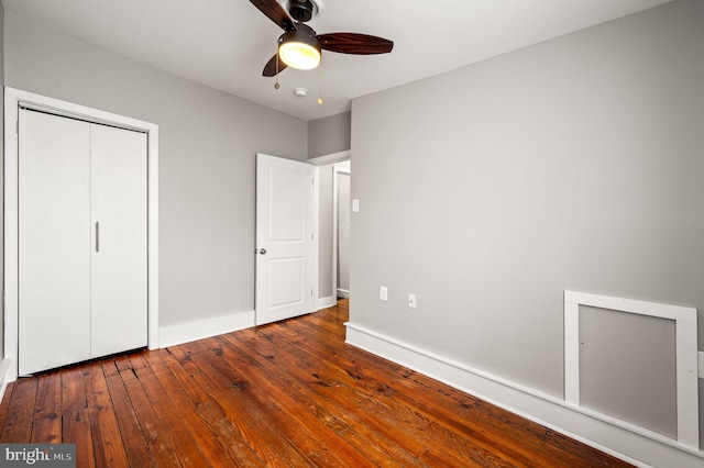 unfurnished bedroom with dark wood-style floors, a closet, a ceiling fan, and baseboards