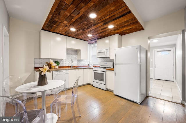 kitchen with white appliances, light wood-style floors, white cabinets, and a sink