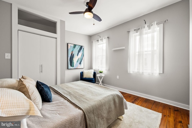 bedroom with a ceiling fan, a closet, baseboards, and dark wood-type flooring