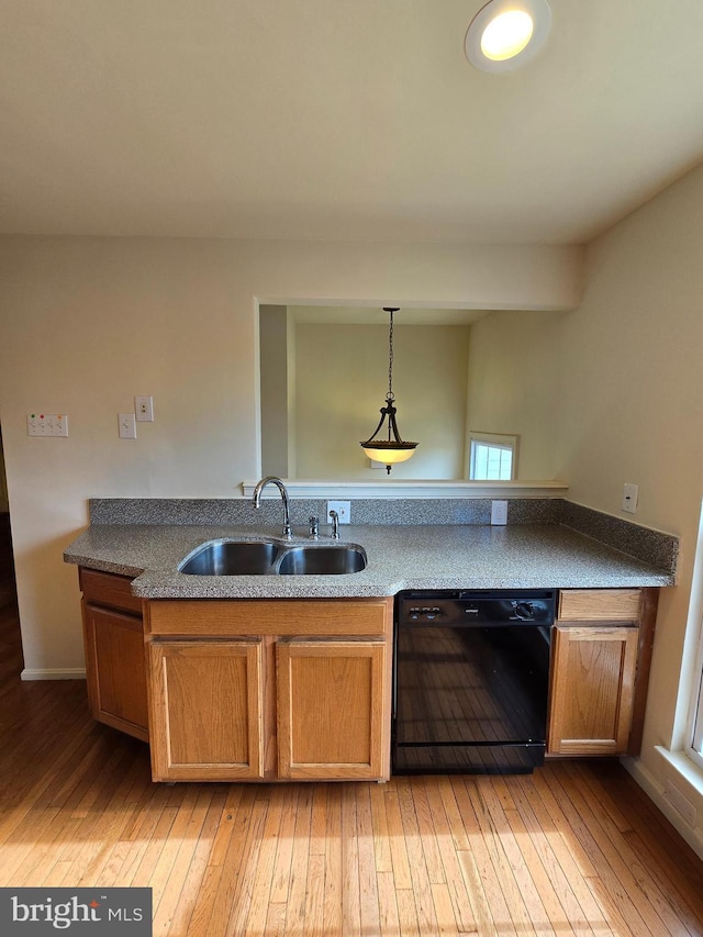 kitchen with black dishwasher, brown cabinetry, a sink, and light wood-style flooring