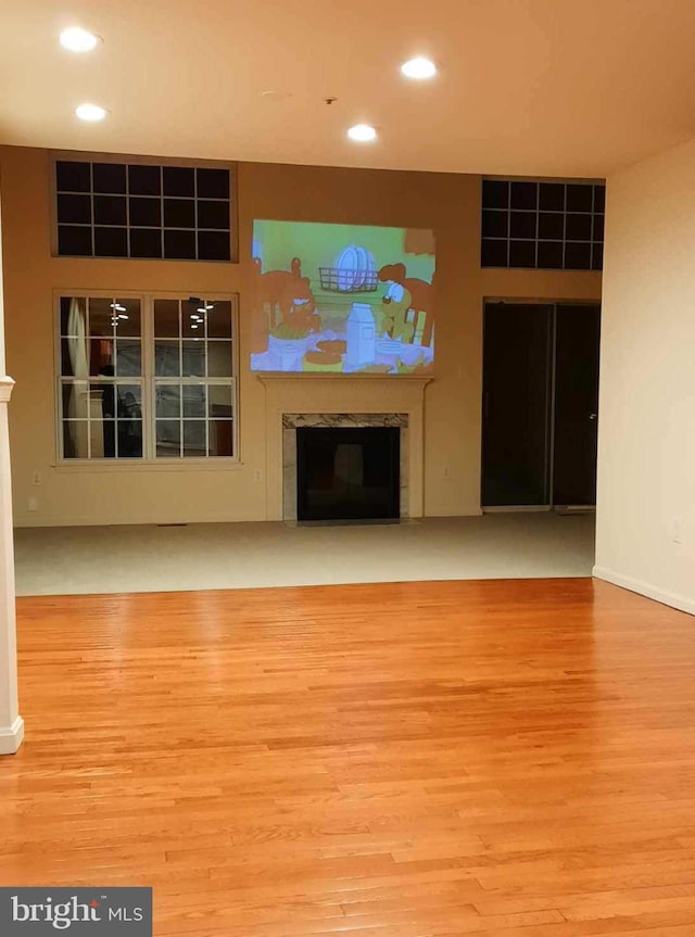 unfurnished living room with a tiled fireplace, wood finished floors, and recessed lighting