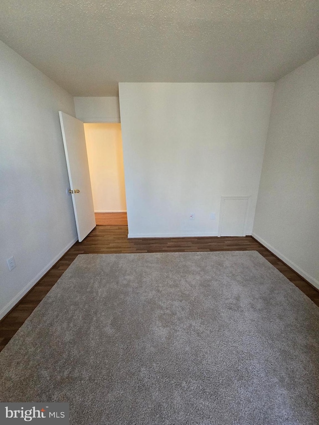 unfurnished room featuring a textured ceiling, baseboards, and dark wood-style flooring