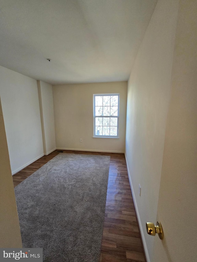 empty room featuring dark wood-style floors and baseboards