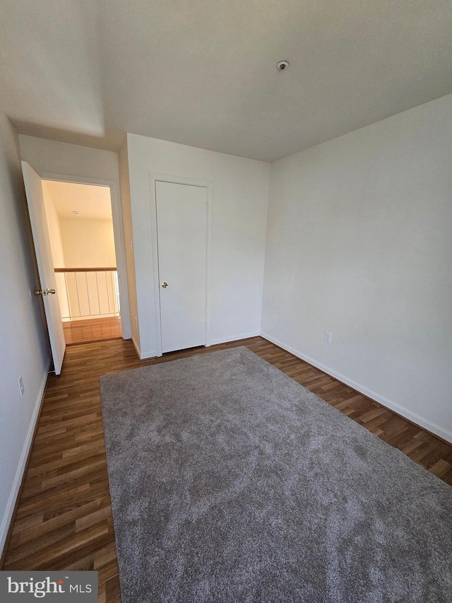 unfurnished bedroom featuring baseboards and dark wood-type flooring