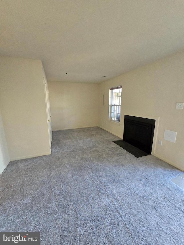 unfurnished living room featuring carpet flooring and a fireplace with flush hearth