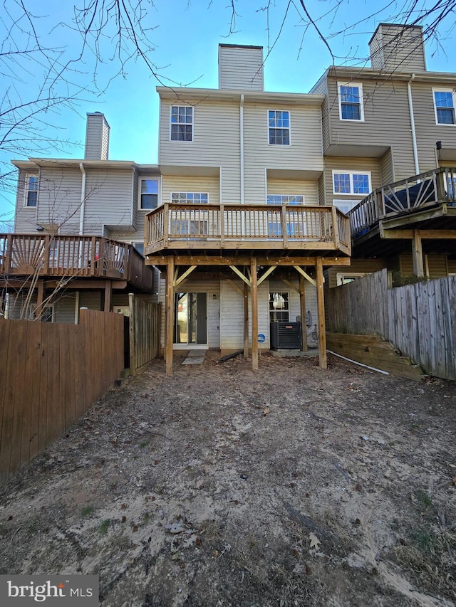 rear view of property with a fenced backyard, a chimney, and a wooden deck