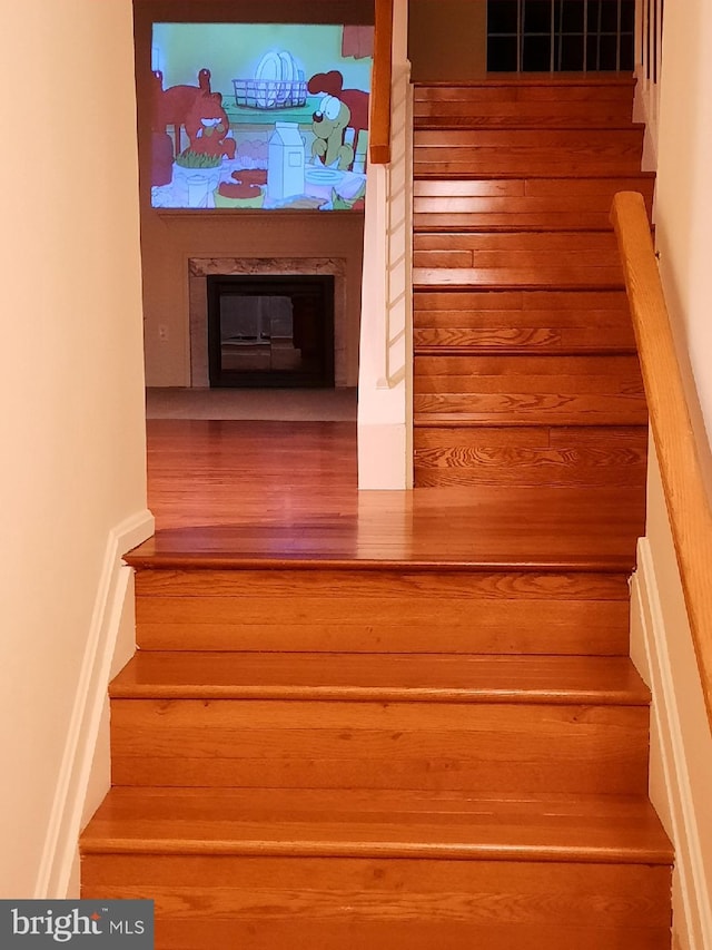 staircase with a glass covered fireplace and wood finished floors