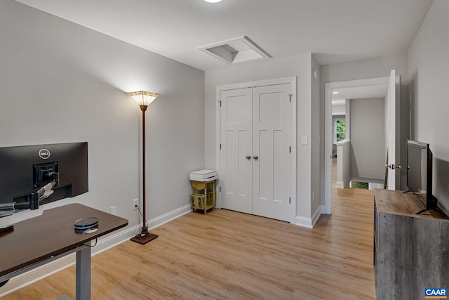 office area with light wood-type flooring, attic access, and baseboards