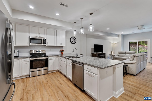 kitchen featuring appliances with stainless steel finishes, open floor plan, a peninsula, white cabinetry, and pendant lighting