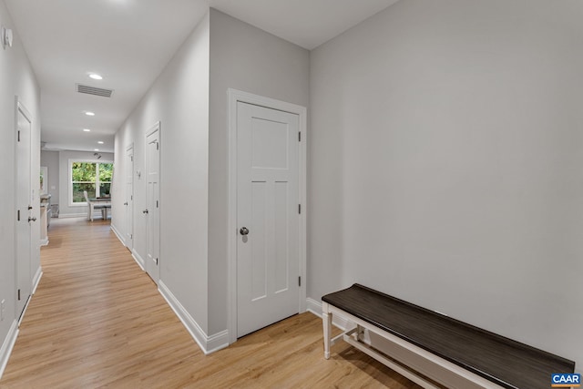 hallway featuring light wood-type flooring, visible vents, baseboards, and recessed lighting