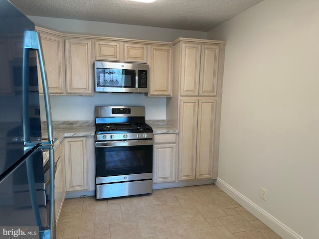 kitchen with baseboards, stainless steel appliances, and a textured ceiling