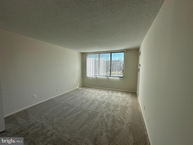 carpeted empty room with a textured ceiling and baseboards