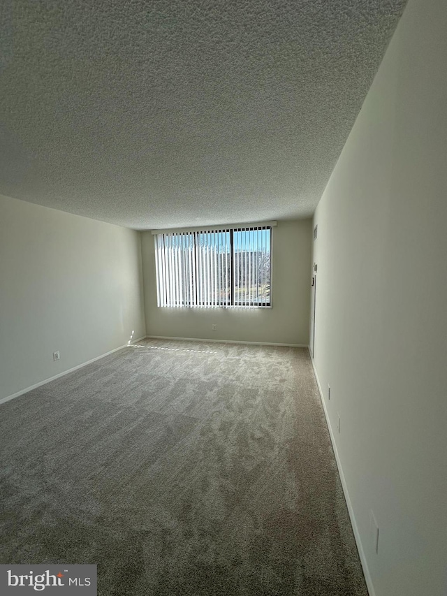 spare room featuring carpet floors, baseboards, and a textured ceiling