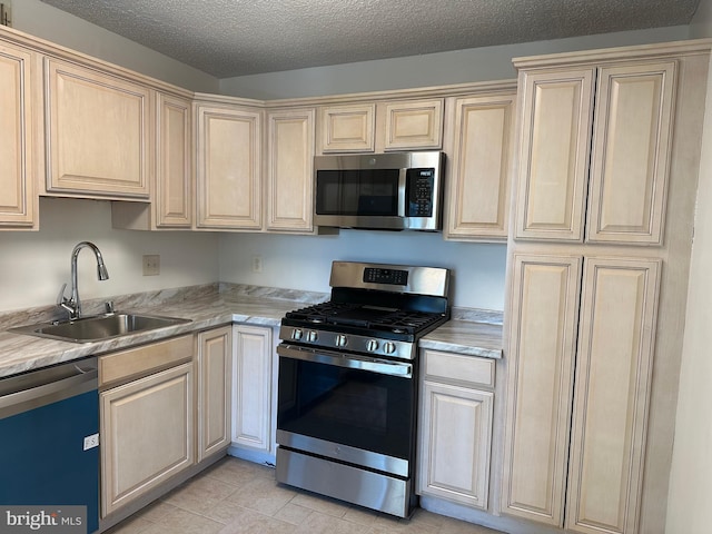 kitchen featuring stainless steel appliances, a sink, and a textured ceiling