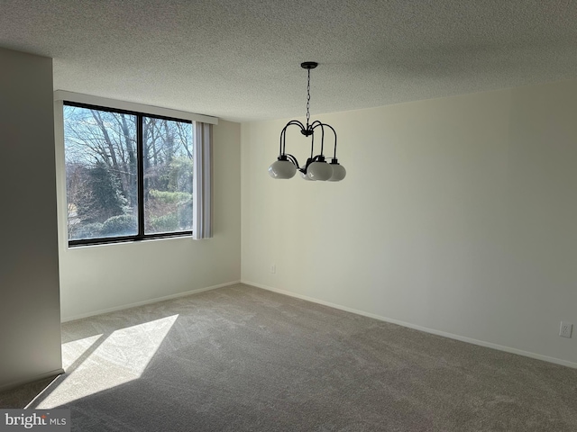 carpeted spare room with baseboards, a chandelier, and a textured ceiling