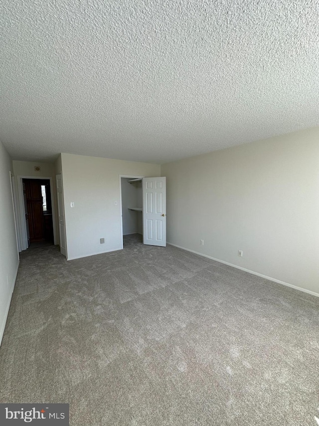 unfurnished bedroom featuring carpet, a closet, a textured ceiling, and baseboards