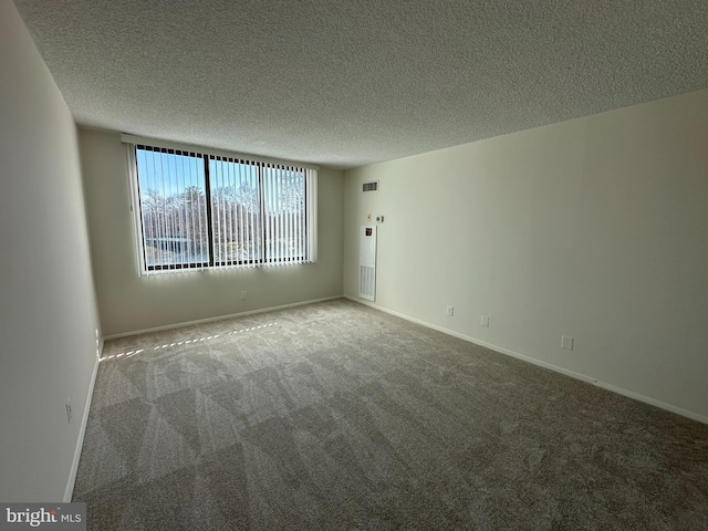 carpeted empty room with baseboards, visible vents, and a textured ceiling