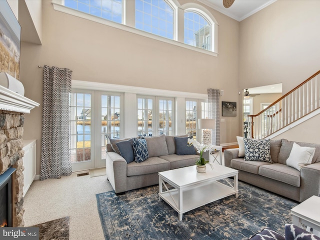 living area with a ceiling fan, a fireplace, a wealth of natural light, and crown molding