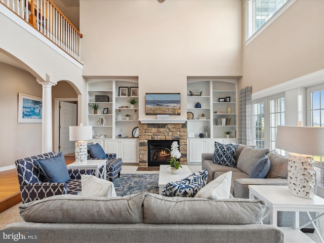 living room featuring a healthy amount of sunlight, ornate columns, a fireplace, and arched walkways