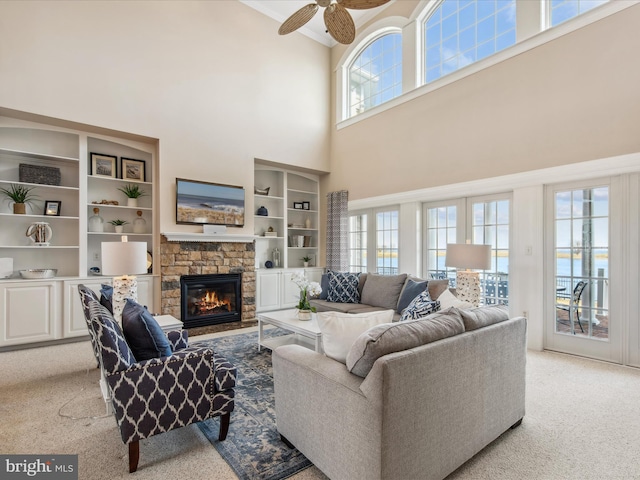 living room with light carpet, a ceiling fan, and a stone fireplace