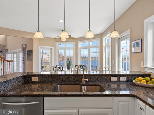 kitchen featuring pendant lighting, white cabinets, a sink, and dishwasher