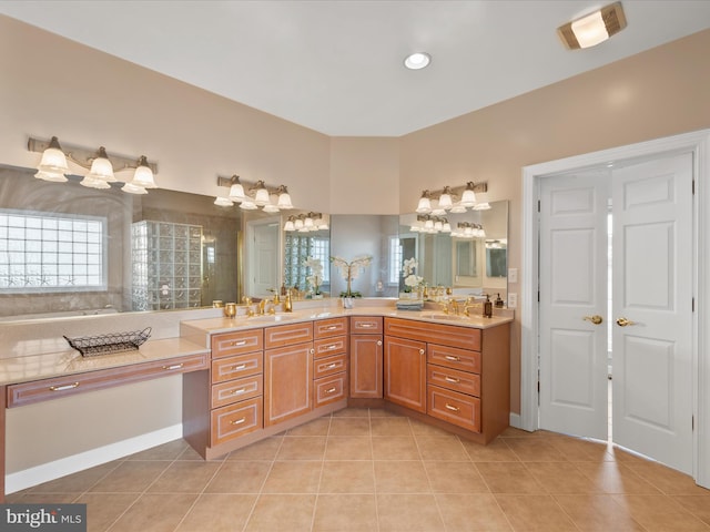 bathroom with a sink, a healthy amount of sunlight, tiled shower, tile patterned floors, and double vanity