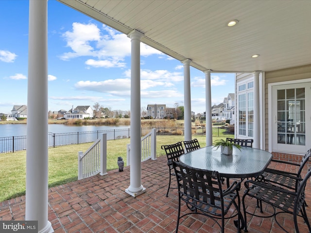 view of patio / terrace with outdoor dining space, a water view, and a fenced backyard