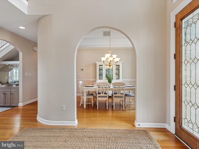 foyer featuring light wood-style flooring, an inviting chandelier, visible vents, and baseboards