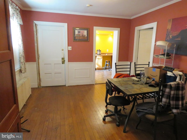 dining room with a wainscoted wall, ornamental molding, radiator heating unit, and hardwood / wood-style flooring