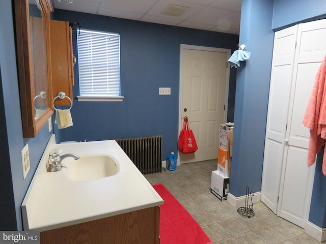 bathroom with baseboards, vanity, a paneled ceiling, and radiator