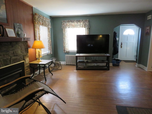 living room with baseboards, wood-type flooring, a fireplace, and radiator