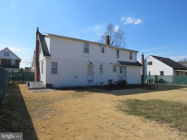 rear view of property with a yard, a chimney, and fence