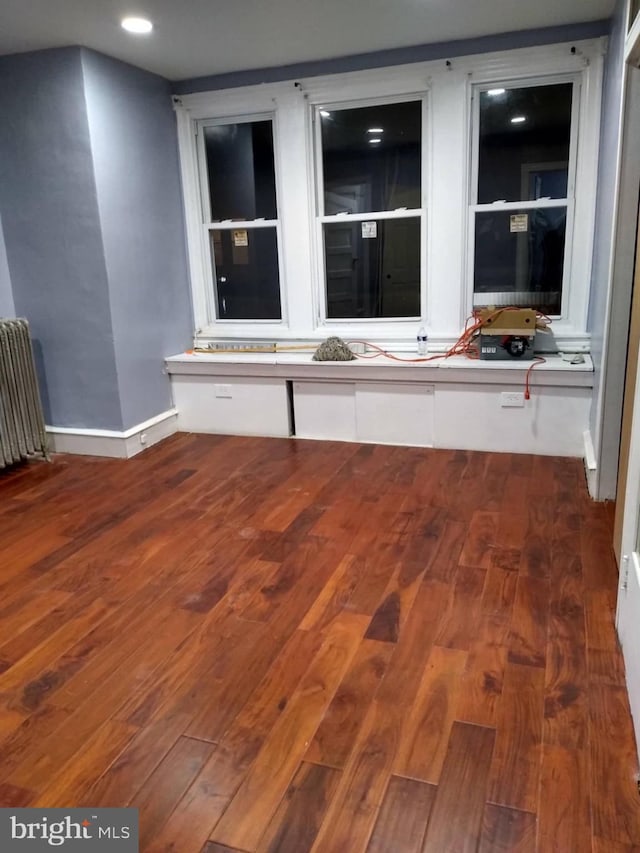 spare room with radiator, dark wood finished floors, and baseboards