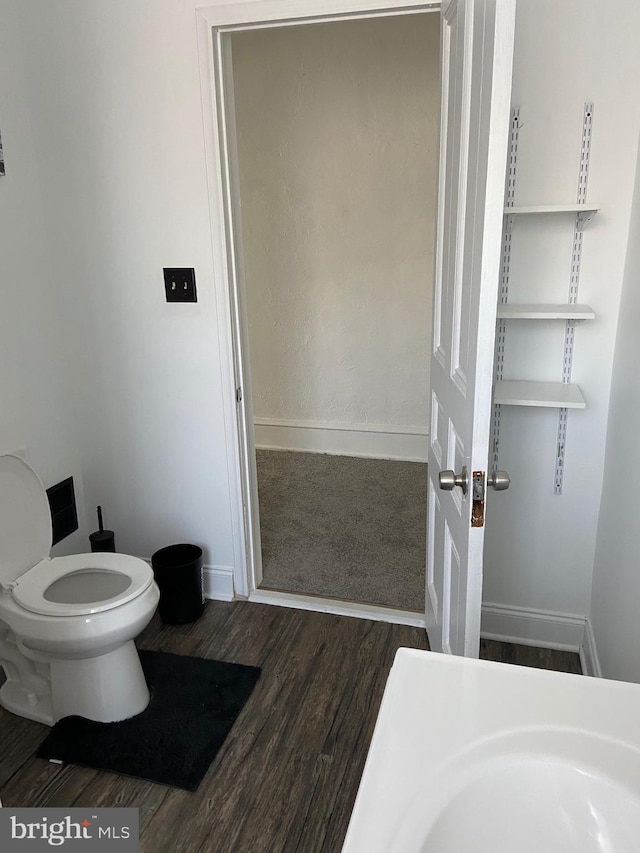 bathroom with toilet, baseboards, and wood finished floors