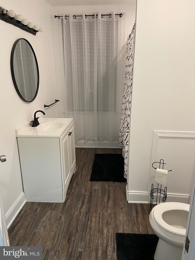 bathroom featuring toilet, curtained shower, wood finished floors, and vanity