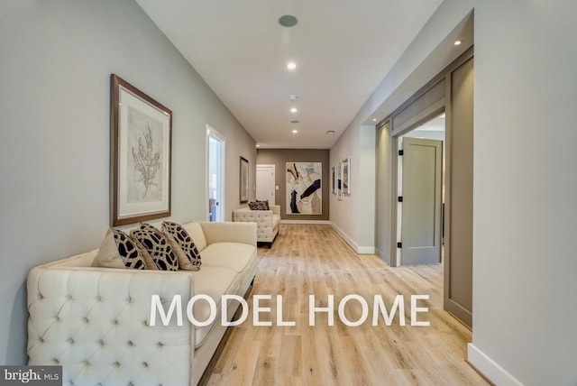 hallway featuring light wood-style floors, baseboards, and recessed lighting