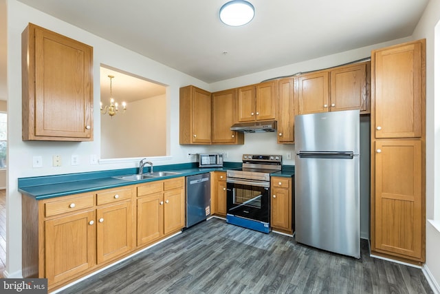 kitchen featuring under cabinet range hood, stainless steel appliances, dark countertops, and a sink