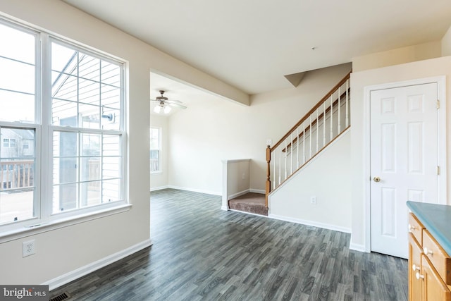 unfurnished living room with stairway, baseboards, dark wood-style floors, and a ceiling fan