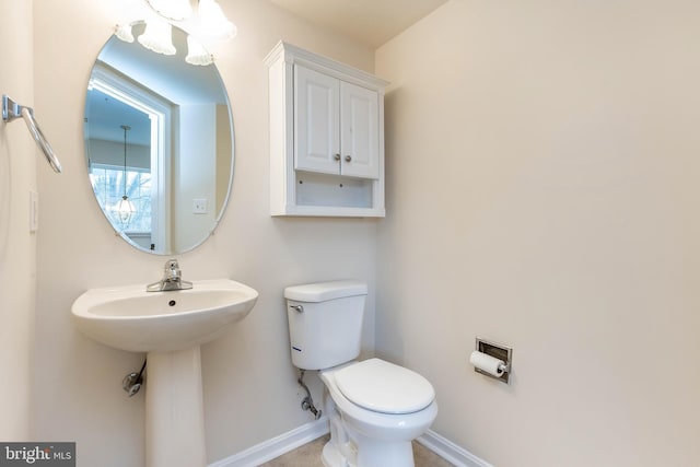 half bath with a sink, baseboards, and toilet