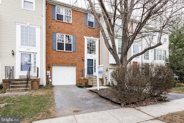 townhome / multi-family property featuring driveway, brick siding, and an attached garage