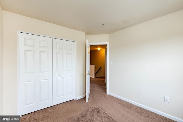 unfurnished bedroom with carpet, baseboards, and a closet