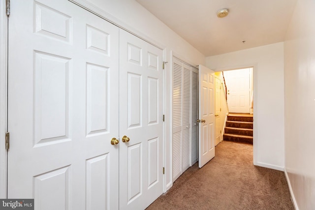 hallway featuring stairway, baseboards, and carpet