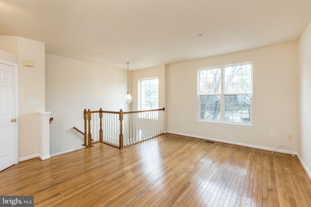 unfurnished room featuring visible vents, light wood-type flooring, and baseboards