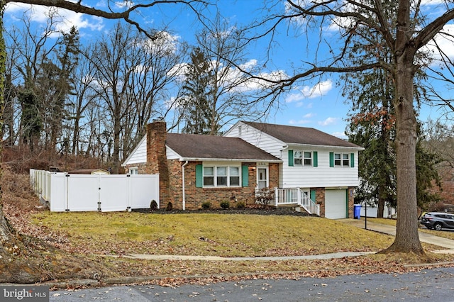 split level home featuring concrete driveway, brick siding, a chimney, and a gate