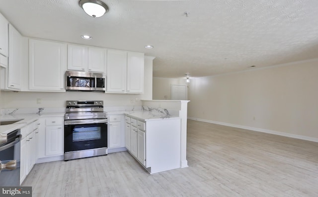 kitchen with light wood finished floors, white cabinets, appliances with stainless steel finishes, a peninsula, and a textured ceiling