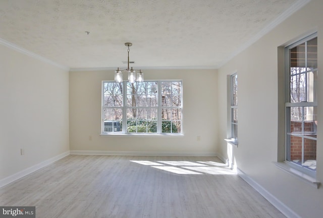 unfurnished dining area with baseboards, a textured ceiling, ornamental molding, and wood finished floors