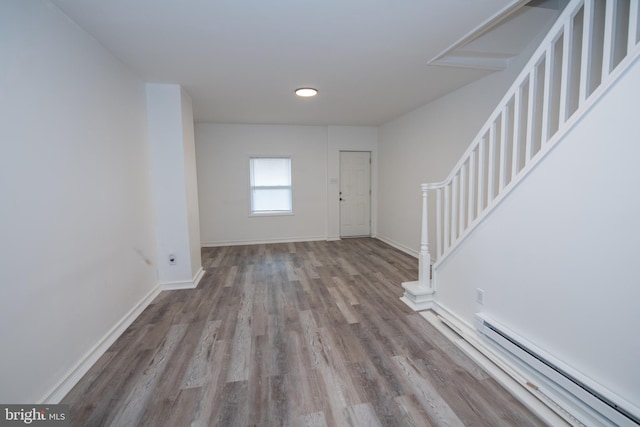 entryway with stairs, baseboard heating, wood finished floors, and baseboards