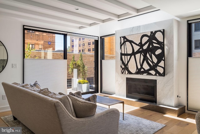 living room featuring beamed ceiling, a premium fireplace, and wood finished floors