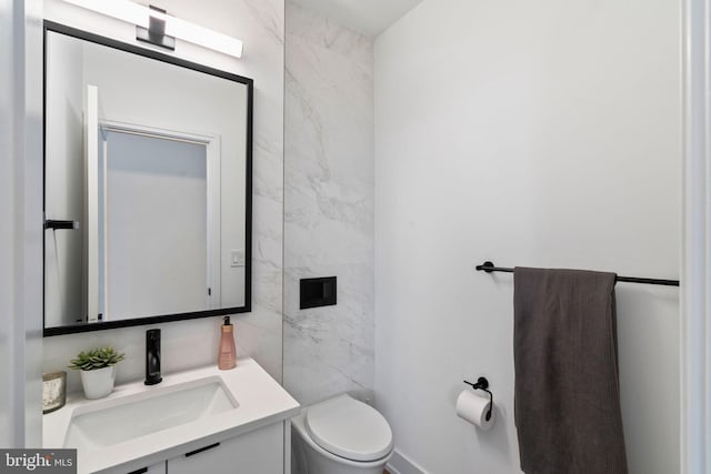 half bath featuring tile walls, vanity, and toilet